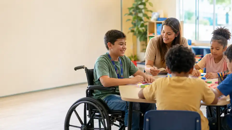 Aluno cadeirante com cordão de autismo aprendendo em grupo com apoio da professora